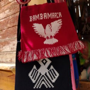 Bolso pequeño tipo chuspa con iconografía andina y correa larga.