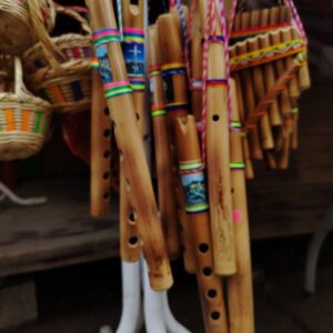 Instrumento musical de viento tipo flauta con grabados étnicos y cintas de colores.
