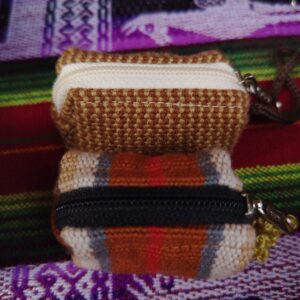 Monedero artesanal tejido en tonos tierra con cierre negro y blanco.