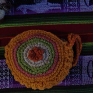 Monedero circular tejido a mano con diseño de flor central en colores naranja y verde.